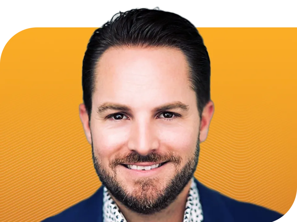 Professional headshot of a smiling man with a beard in a blue suit jacket against a yellow background with wavy white lines.