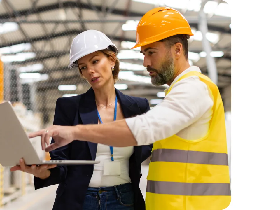 Logistics and warehouse professionals reviewing supplier collaboration data on a laptop in a production facility.