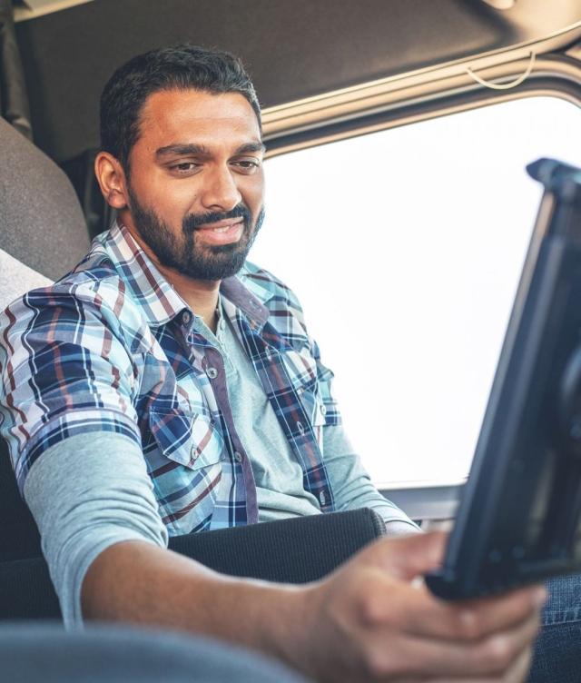 Truck Driver looking at tablet in cab