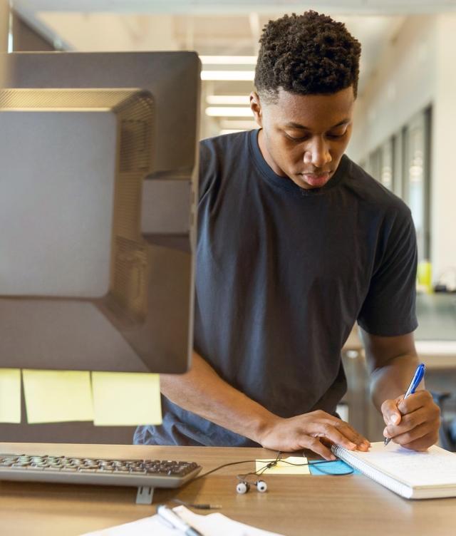 Man making notes next to computer using TMS