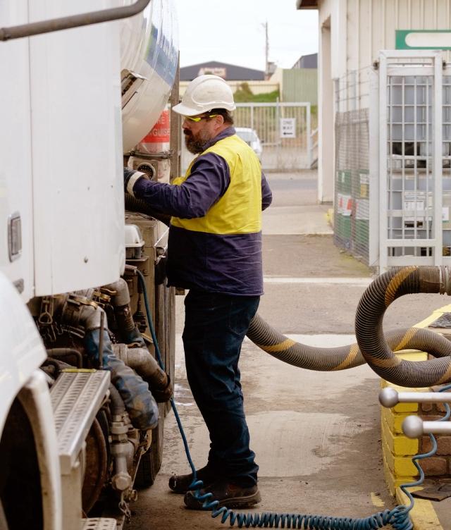Man unloading fuel truck at stop