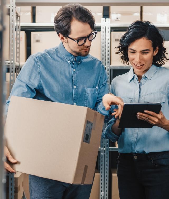 two people checking TMS status in warehouse with boxes