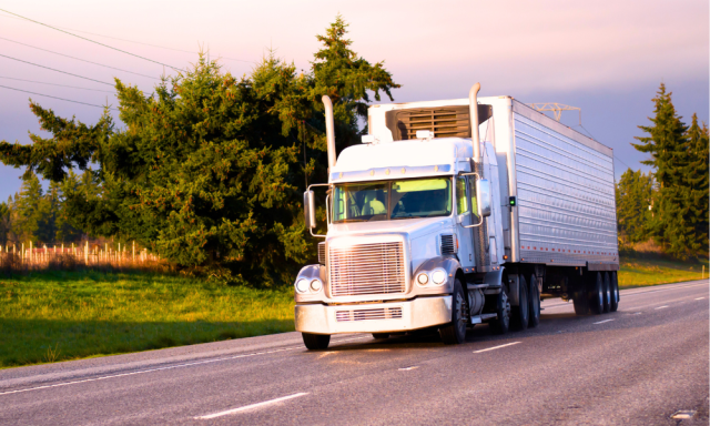 Refrigerated dry van semi truck driving down the road